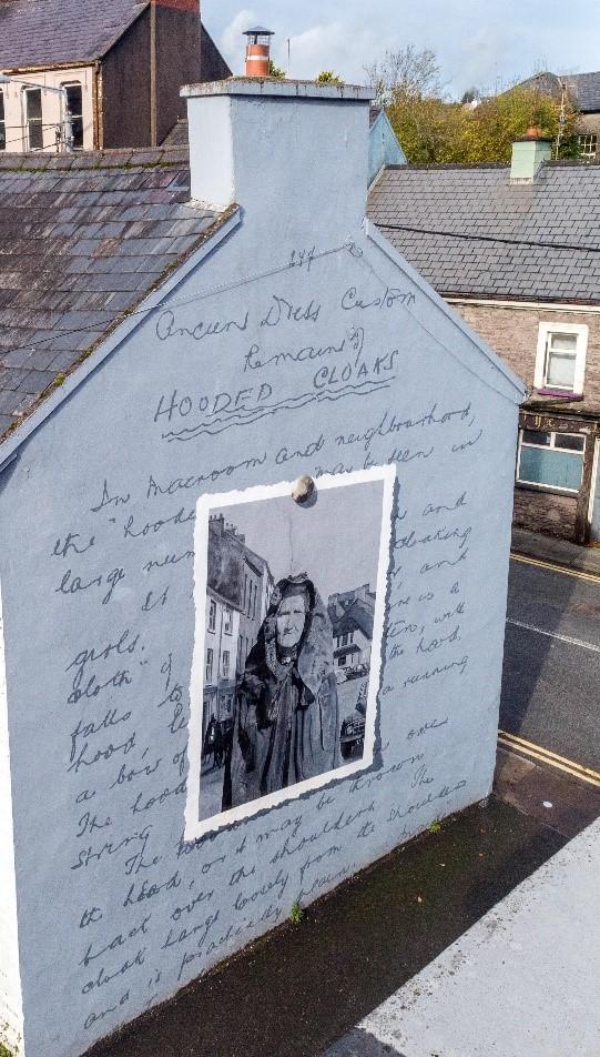 A mural on the gable end of a house depicting the handwriting and an old picture