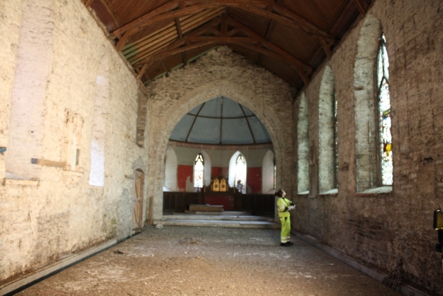 Church of Ireland in Macroom undergoing construction a worker is look at a large window in the empty church