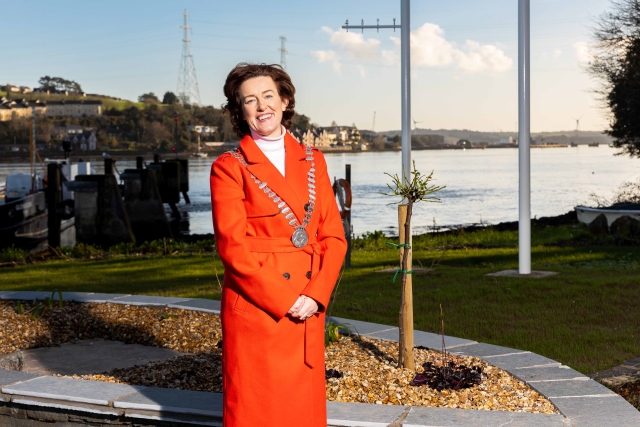 A photograph of the Mayor of the County of Cork standing beside the sea in a village in County Cork