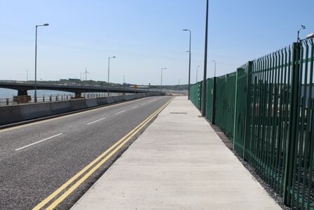 A road with a green fence on the side