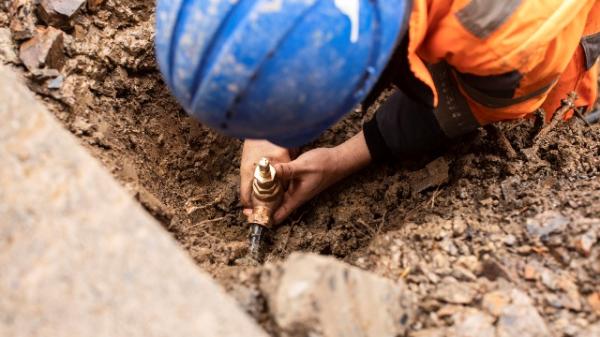 A stock image of someone repairing piping in the ground.