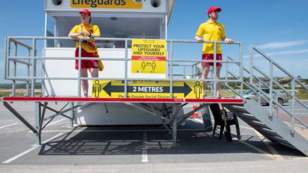 2 lifeguards on duty atop a life hut in a car park