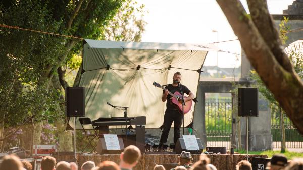 Mick Flannery performing on stage with his guitar to a crowd