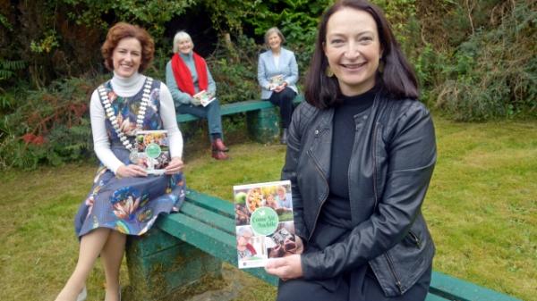 Emer O'Brien, County Librarian, Mayor of the County of Cork, Gillian Coughlan, author Alice Taylor and Deirdre Murphy Cork County Council Library Age Friendly Services. sitting on two benches in an outdoor setting holding the promoted collection of poems and short stories