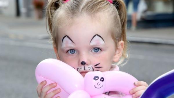 Girl in facepaint with cute balloon animal