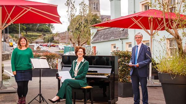 Mayor and Community Representatives in front of a Piano outdoors in Bandon