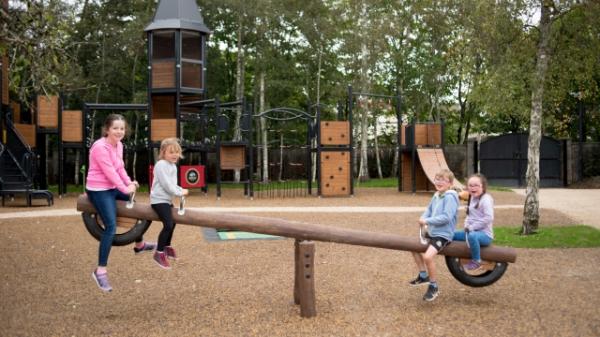 4 children playing on a see-saw in the new Mallow playground with the playground in the background