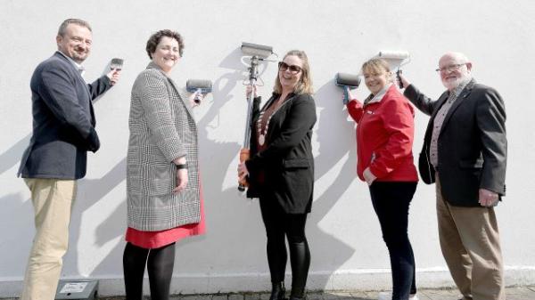 MD Officials and Councillors with rollers, painting a wall.