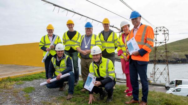 A group of people wearing safety vests and standing next to a body of water