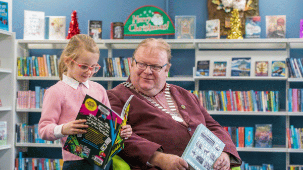 A man in a suit and a schoolgirl reading books in a library