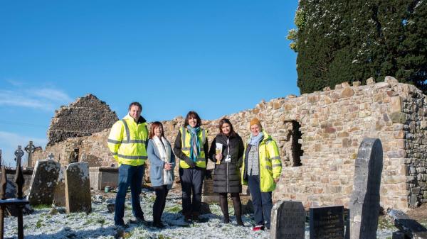 A group if people in high visibility vest standing in a ruined church