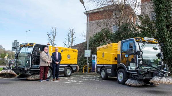 2 men standing next to two sweepers.