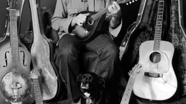 A man sitting with guitars in the background