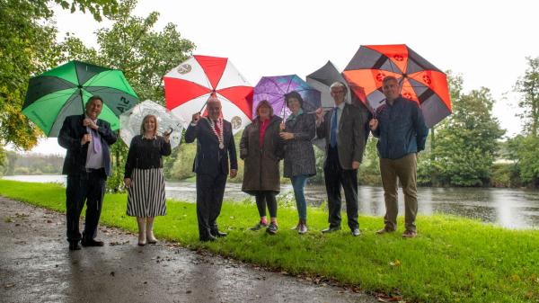 A group of people on a walkway with umrellas in the rain