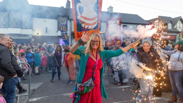 A woman on a crowded street waving a sparkler