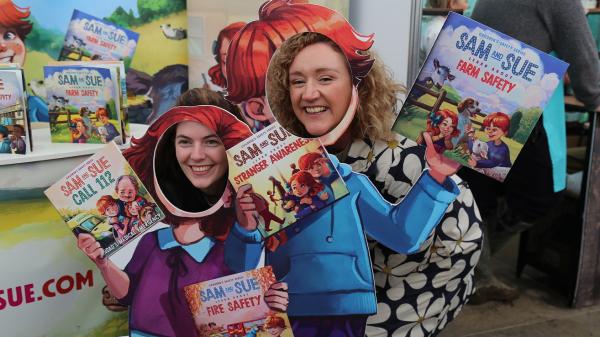 Two women posing in cardboard cutouts promoting Sam and Sue books.
