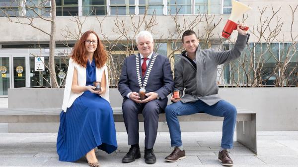 The Mayor of the County of Cork, Cllr. Frank O'Flynn sitting next to a man and a woman on a bench