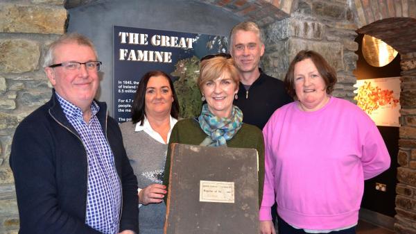 5 people, one of whom is holding a burial register record book.