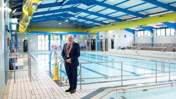 A man in a suit standing near a wimming pool