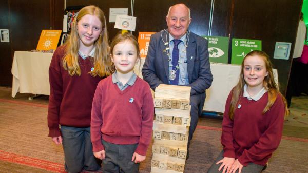 A man and a group of children standing beside jenga blocks