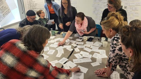 A group of people around a table writing on pieces of paper