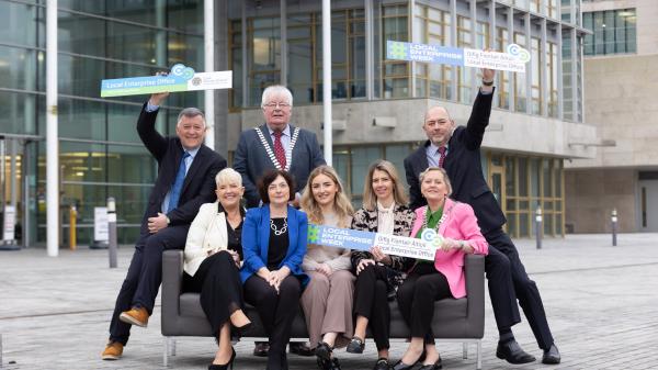 Mayor Joe Carroll and members of LEO's in Cork sitting on couch outside County Hall while holding LEO week signs.