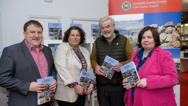 Moira Murrell along with two men and one woman holding Retail Heritage Book