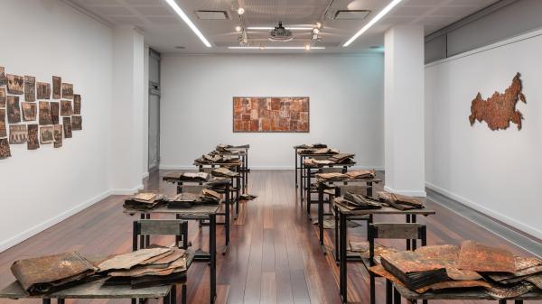 Art Installation in LHQ gallery with a number of desks with art on them.