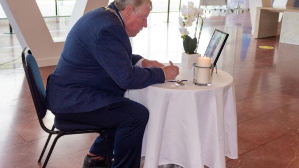 A person sitting at a table signing a book of Condolence.