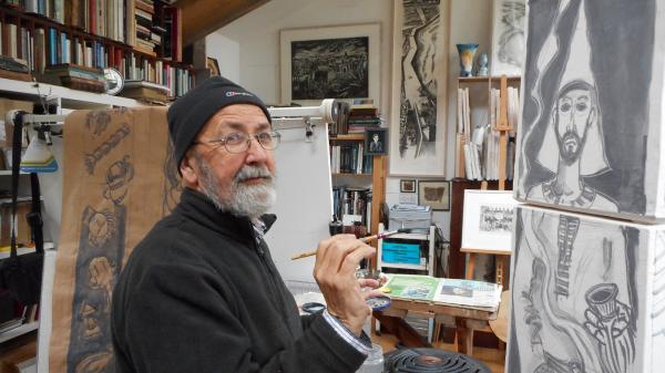 Brian Lalor holding a paintbrush in front of a canvas.