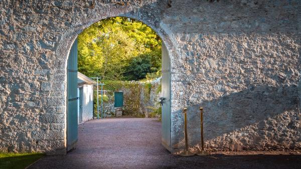Stone wall with doorway into garden.