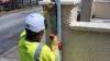 A person in a safety vest holding an object working on a lighting pole