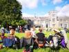 A group of people sitting in chairs in a grassy area with a building in the background