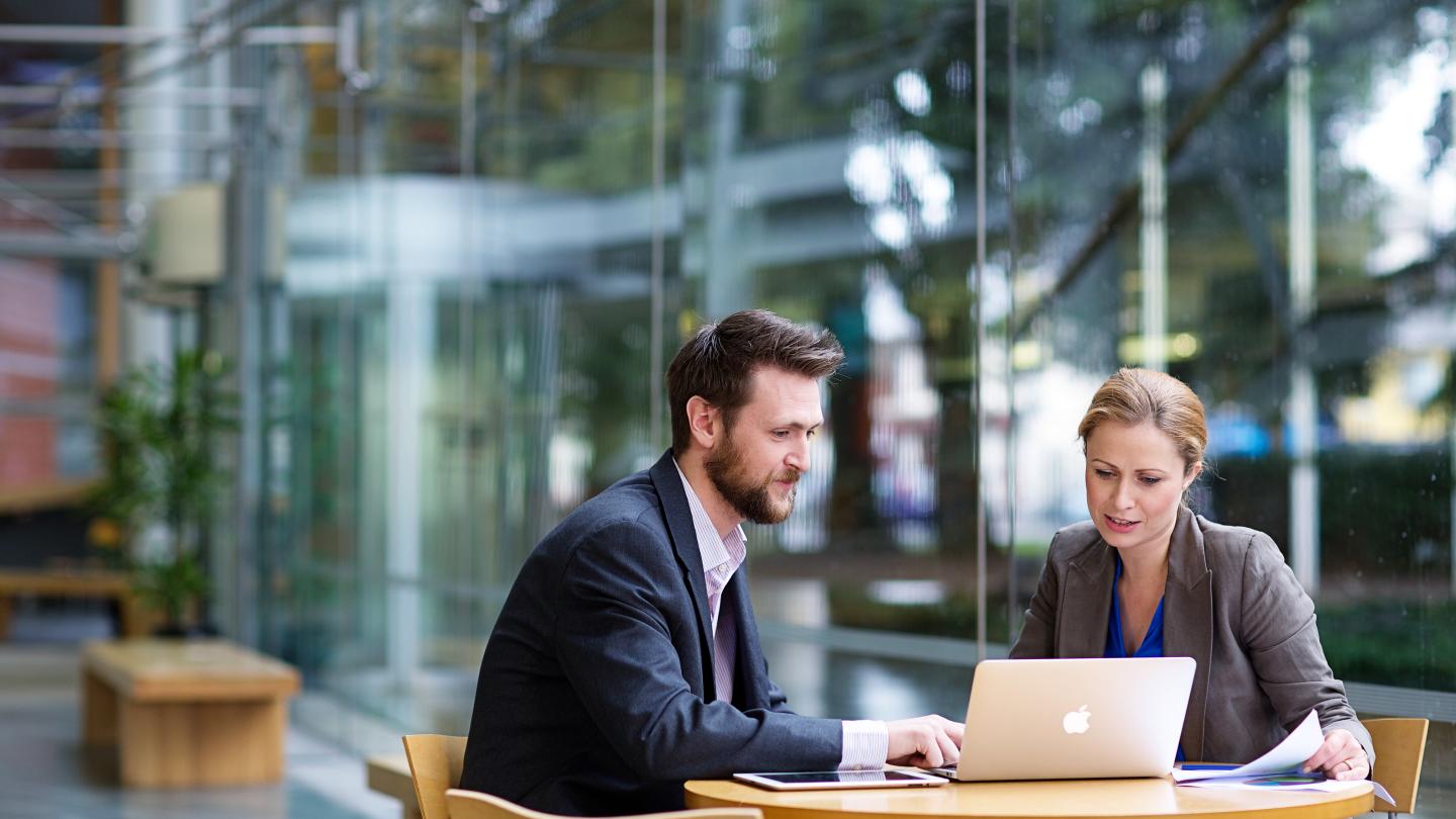 Business man and women sitting at desk with laptop