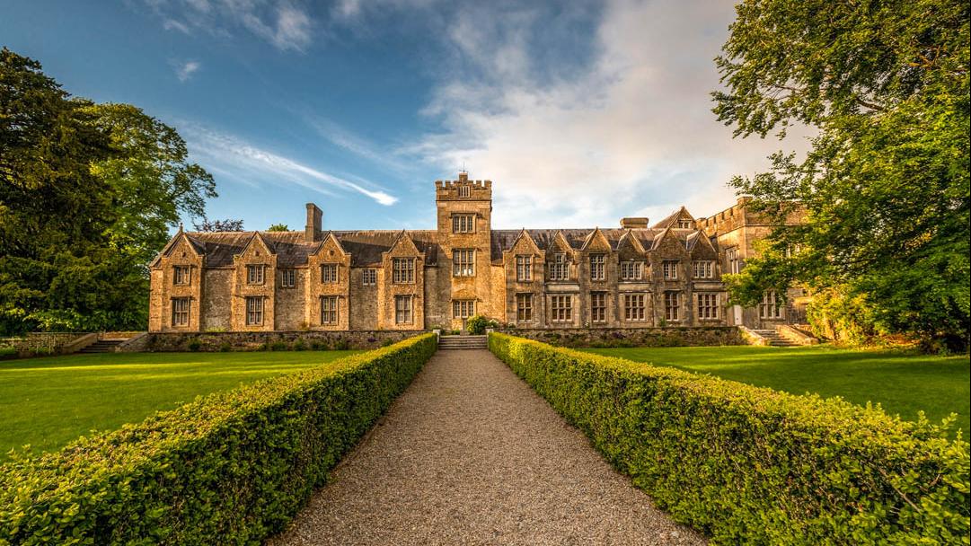 A castle with a lawn and path in front with blue sky overhead