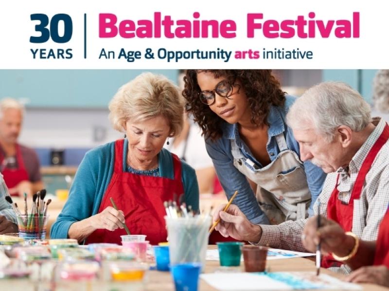Attendees celebrating at Bealtaine Festival, surrounded by colourful banners and engaging in various cultural activities.