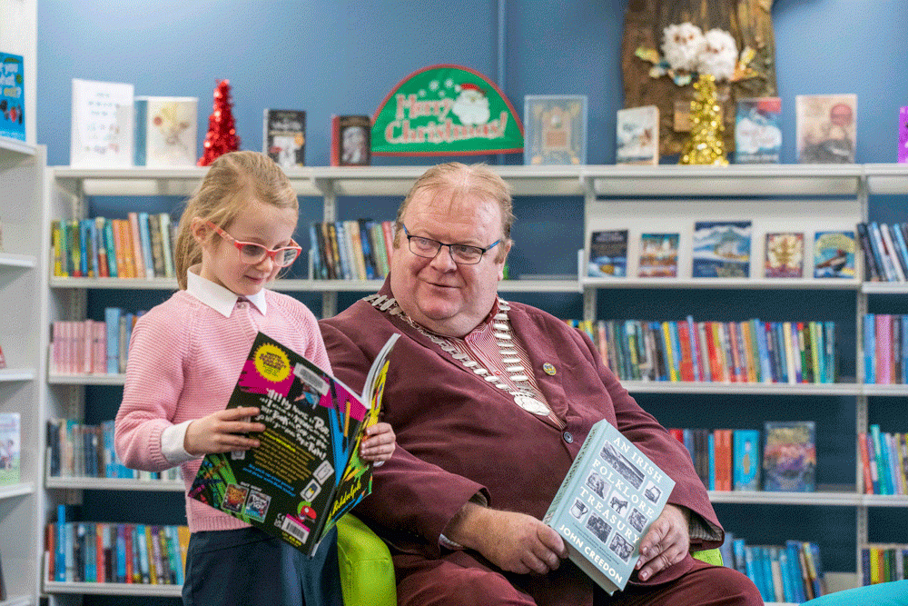 A man in a suit and a schoolgirl reading books in a library