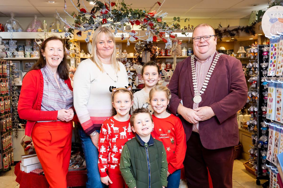 A group adults and children under a christmas decortaion