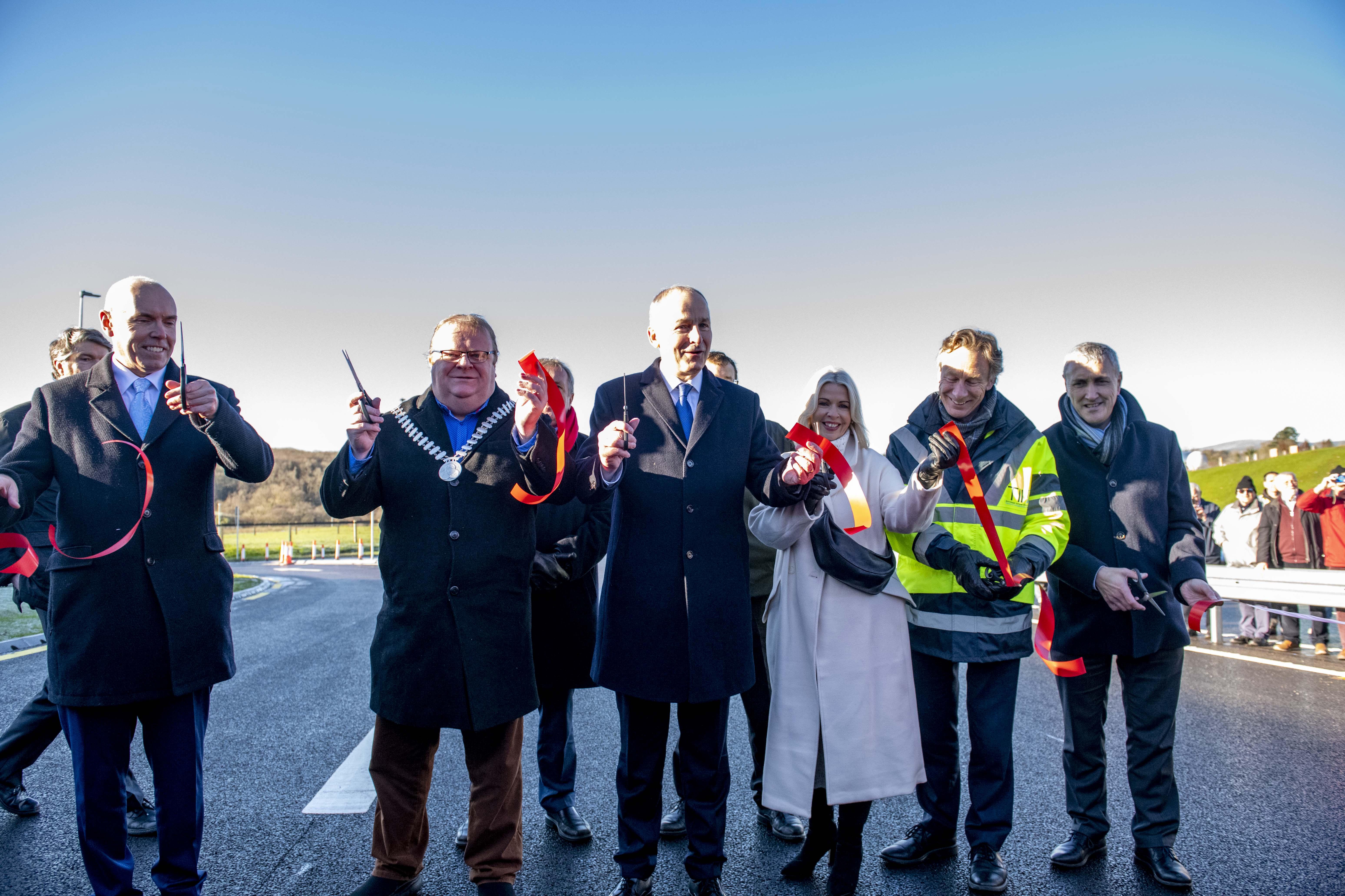 A group of people in suits cutting a ribbon