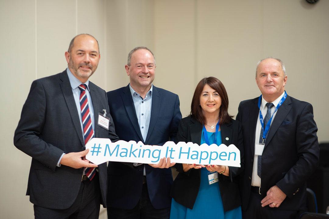 A group of people posing for a photo holding a cut with the text 'Make it Happen'