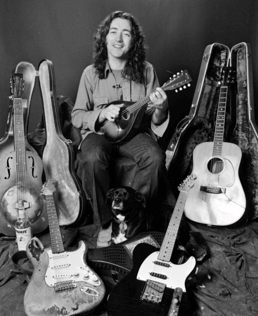 A man sitting with guitars in the background