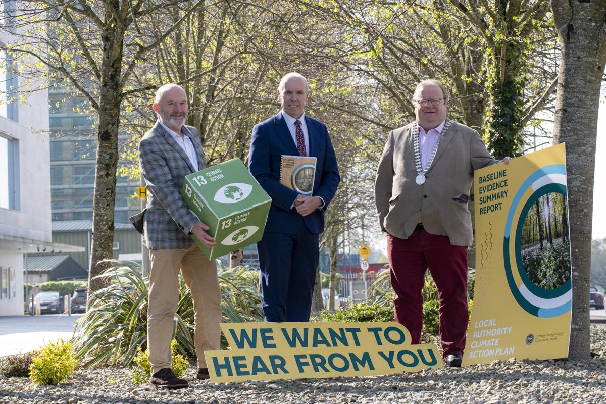 Three people standing in a open space with holding promotional Material