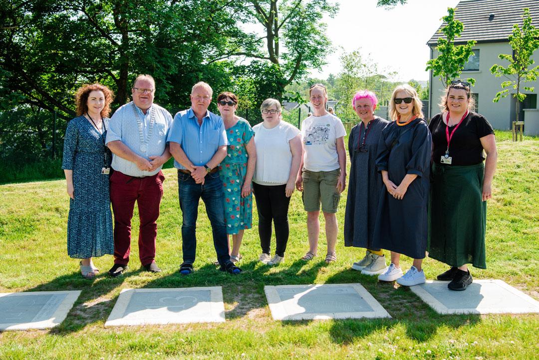 A group of people standing in front of a art installation on a summers day