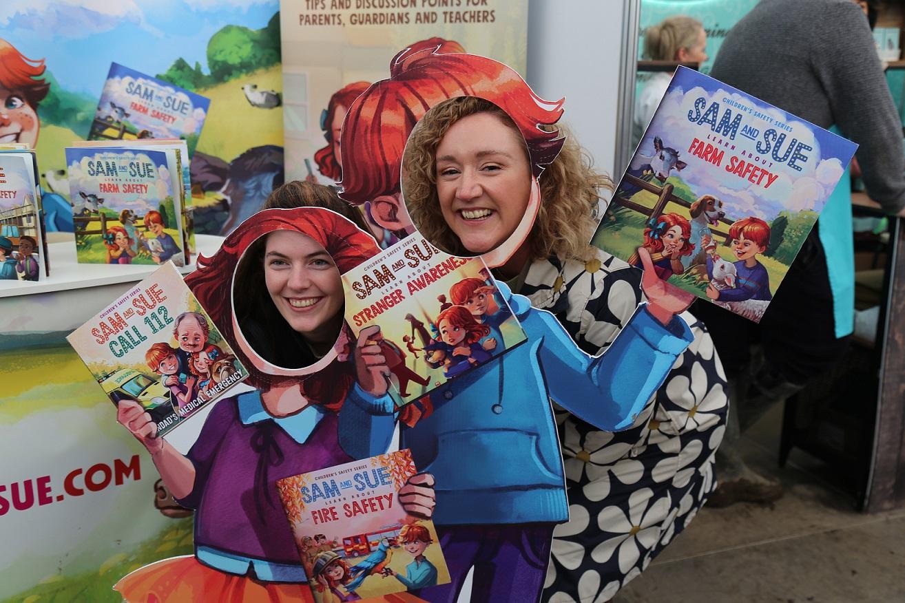 Two women posing in cardboard cutouts promoting Sam and Sue books.