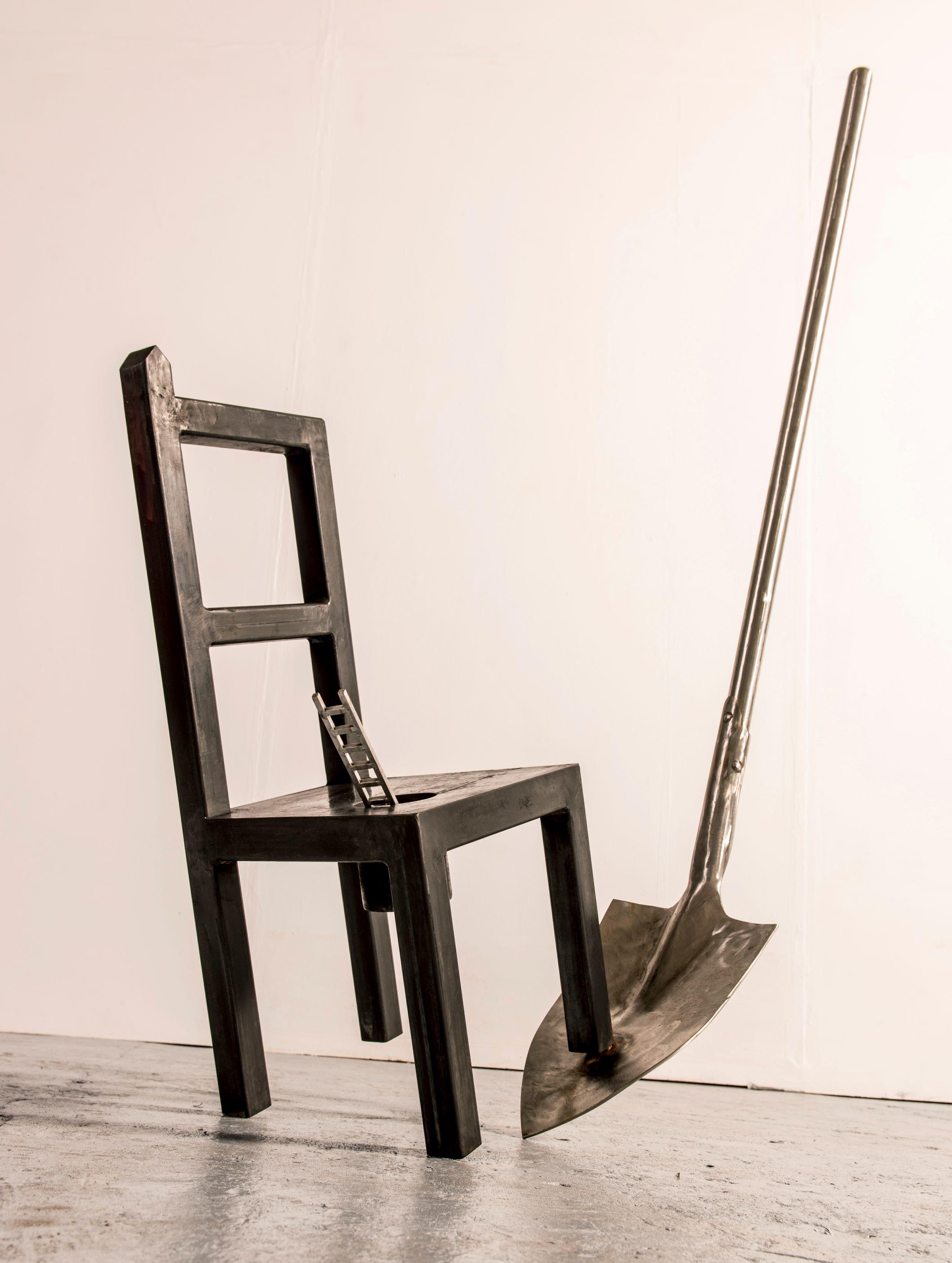 sculpture depicting a chair, spade and miniature ladder balanced upon each other.