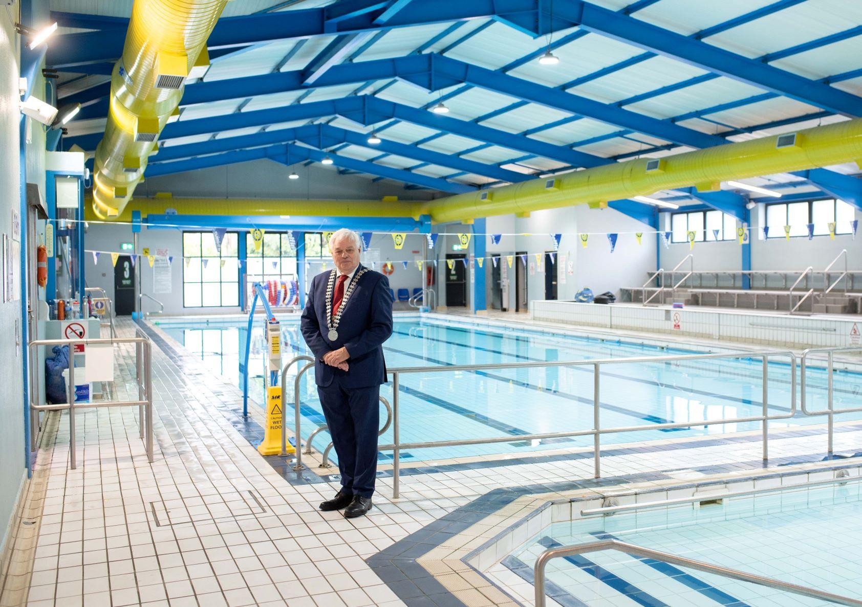 A man in a suit standing near a wimming pool