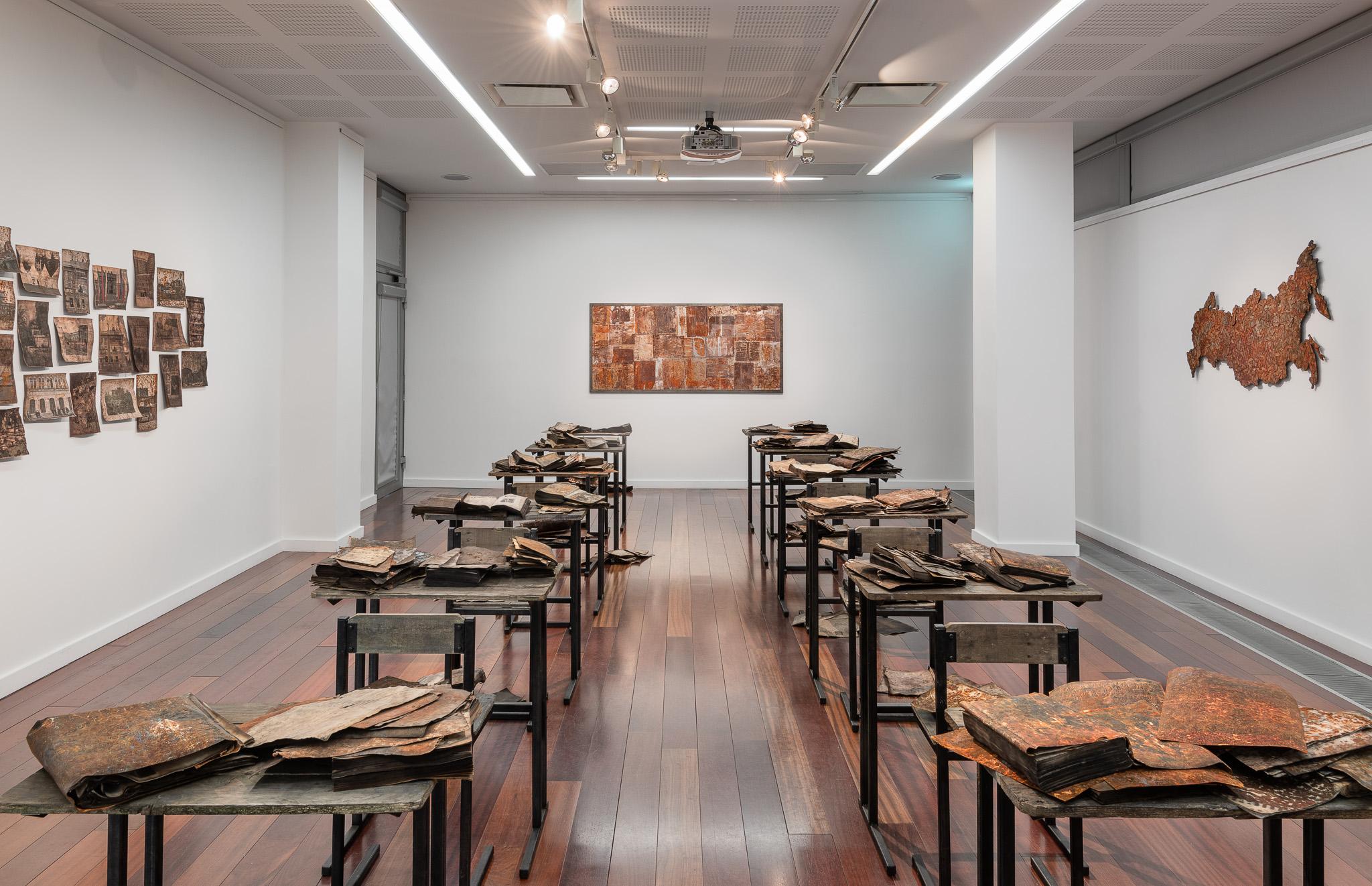 Art Installation in LHQ gallery with a number of desks with art on them.